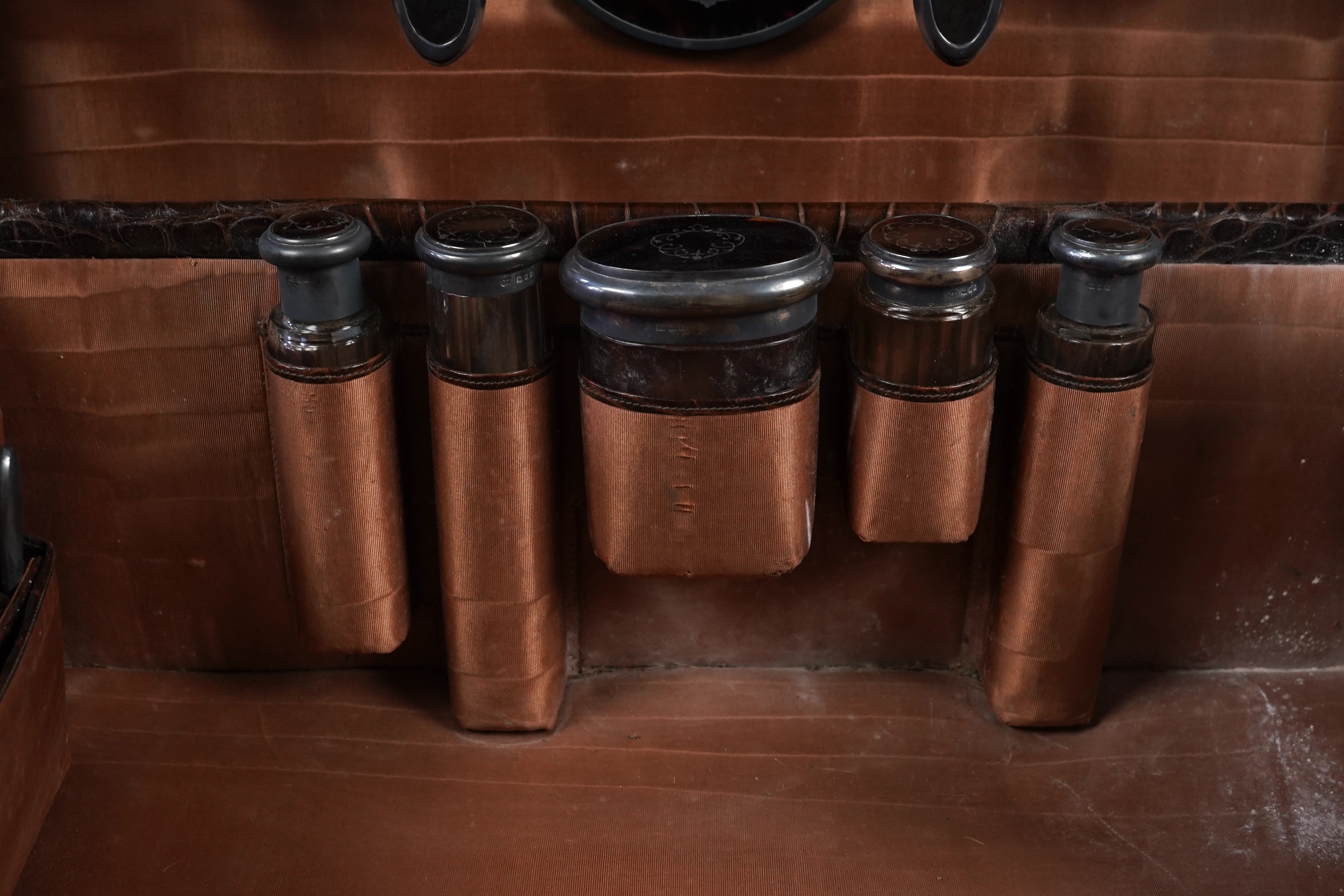 A George V crocodile skin travelling toilet case, containing twelve silver and tortoiseshell mounted accoutrements, by Collet & Anderson